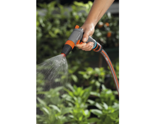 Eine Hand hält eine Gartenspritze, die Wasser versprüht.