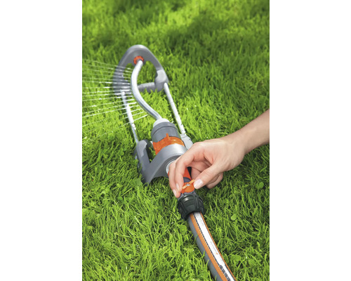 Rasensprenger in Betrieb mit Hand am Regler auf Rasen