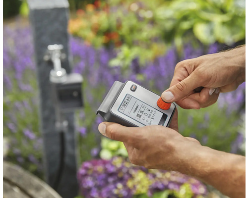 Eine Person bedient eine elektronische Bewässerungssteuerung für den Garten.