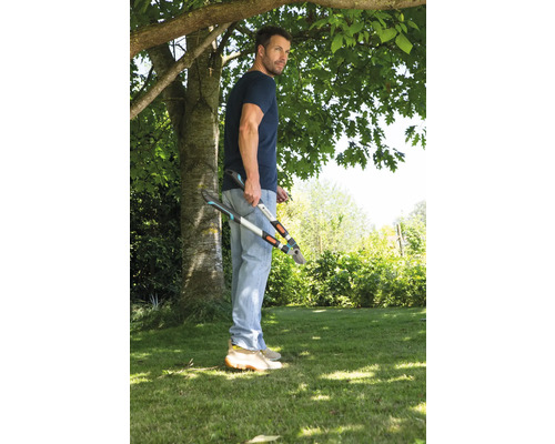 Ein Mann steht im Garten und hält eine Astschere.