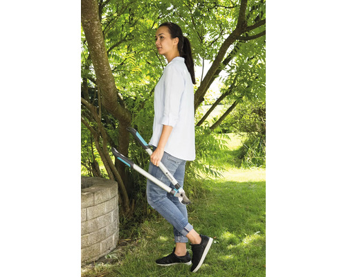 Une femme se tient dans le jardin et tient un ébrancheur à la main.