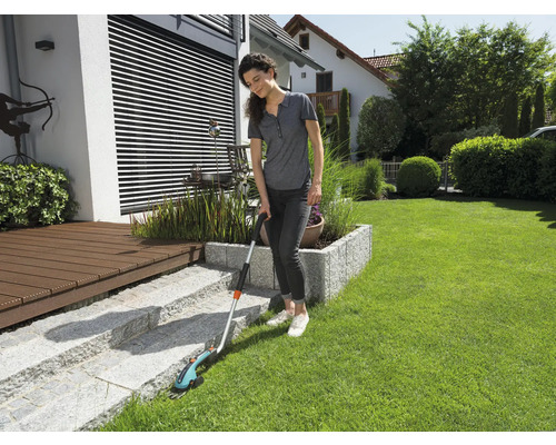Une femme utilise des cisailles à gazon sans fil pour tailler les bordures d''un jardin.