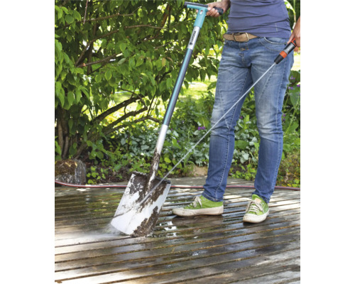 Person reinigt eine Terrasse mit einem Gardena Terrassenreiniger und einem Wasserschlauch