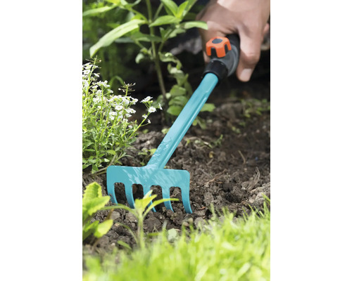 Jardinage avec un petit râteau dans le parterre.