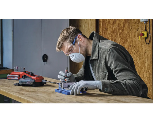 Ein Mann arbeitet mit einem Akku-Multifunktionswerkzeug, geschützt durch Sicherheitsausrüstung.