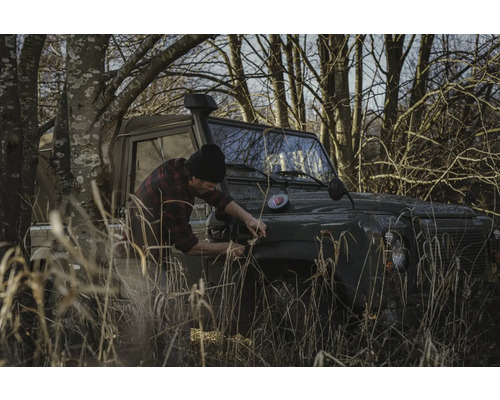 Un homme fixe quelque chose sur un véhicule tout-terrain sur le terrain