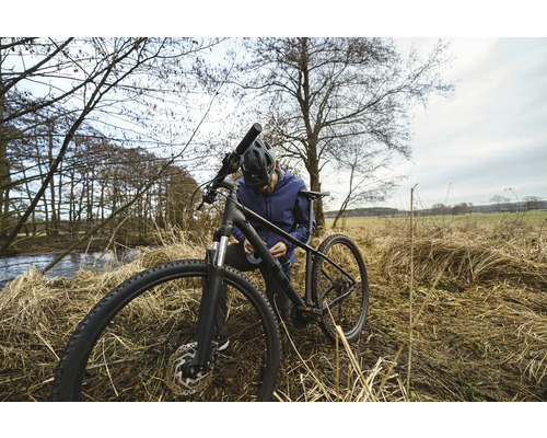 Un homme répare son vélo dans la nature