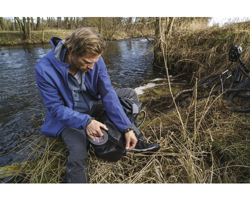 Homme avec du ruban adhésif au bord d''une rivière, à côté d''un vélo.