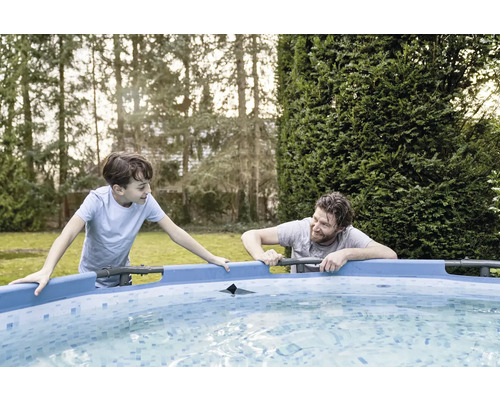 Un père et son fils se tiennent près d''une piscine dans le jardin.