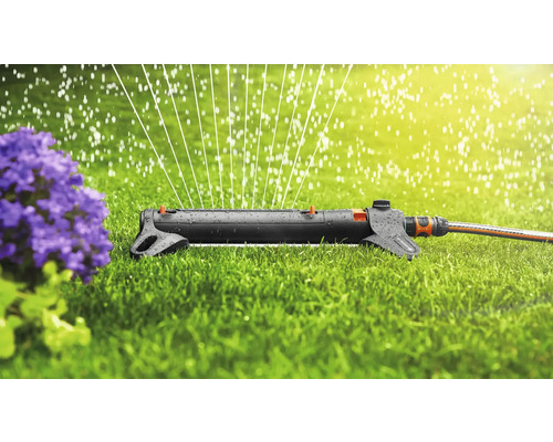 Arroseur de pelouse arrosant une pelouse près d''une plante