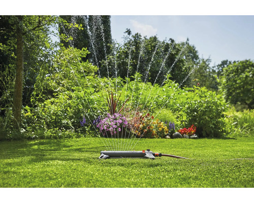 Arroseur de pelouse dans le jardin arrosant la pelouse