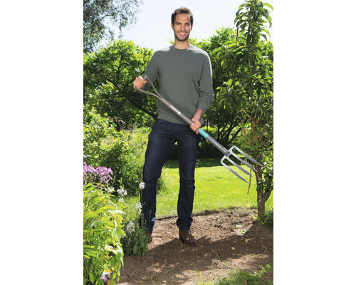 Ein Mann steht im Garten und hält eine Grabegabel.