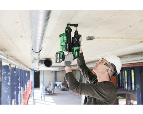 Un homme portant des équipements de protection utilise un perforateur sans fil HiKoki sur un plafond.