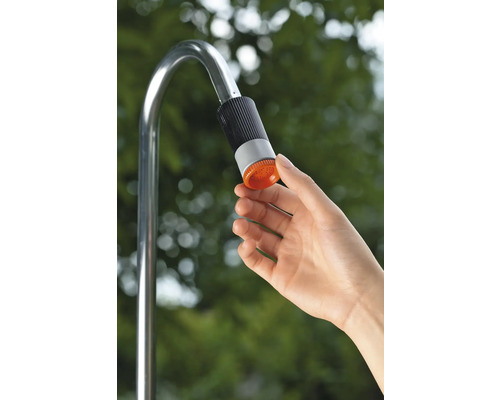 Hand betätigt den Duschkopf einer Gartendusche aus Metall.