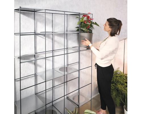 Femme plaçant une plante en pot dans une étagère métallique avec des jardinières