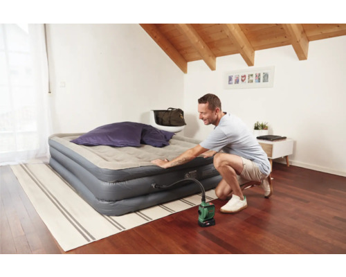 Mann pumpt eine Luftmatratze mit einer elektrischen Pumpe in einem Raum auf