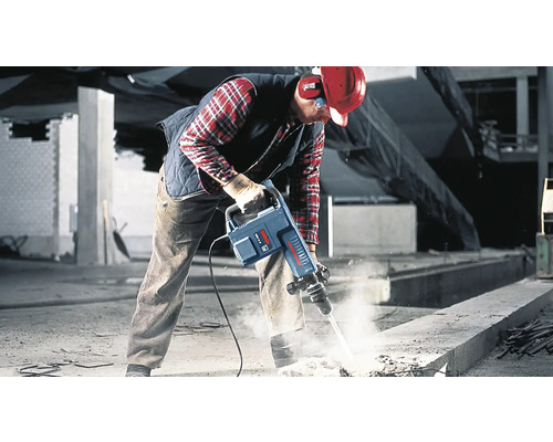 Un ouvrier utilise un marteau-piqueur sur un chantier pour casser du béton.