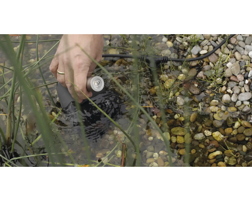 Hand platziert Unterwasserlampe in Teich