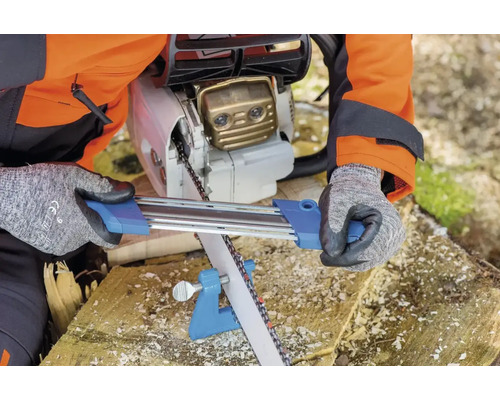 Une personne affûte la chaîne d''une tronçonneuse avec un affûte-chaîne.