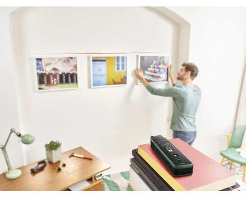 Un homme accroche des photos à un mur avec un détecteur.
