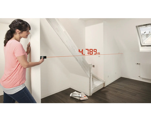 Femme mesurant une pièce avec un télémètre laser