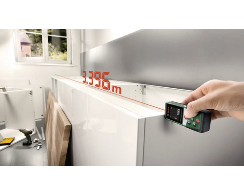 Main avec télémètre laser Bosch mesurant un meuble