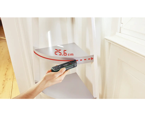 Une main mesure 25,6 centimètres avec un télémètre numérique.