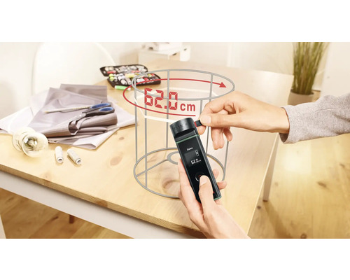 Une personne mesure un abat-jour avec un appareil de mesure numérique sur une table