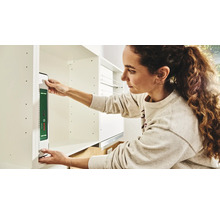 Femme fixe un niveau à bulle Bosch sur une armoire