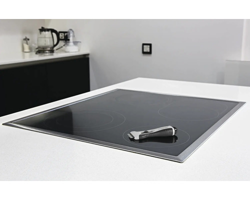 Glaskeramikkochfeld mit Reinigungsschaber in einer modernen Küche.