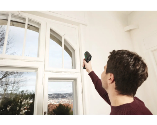 Mann misst Temperatur an Fenster mit Thermometer