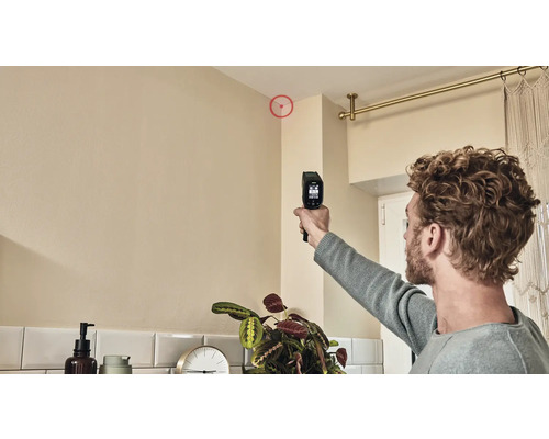 Ein Mann benutzt ein Feuchtigkeitsmessgerät, um die Ecke einer Wand zu prüfen