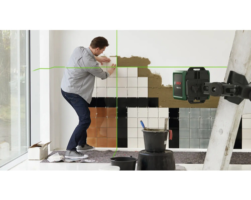 Un homme pose des carreaux avec un laser lignes croisées Bosch