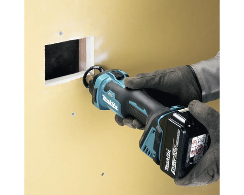 Logo Makita. Scie à plaques de plâtre en utilisation sur un mur.