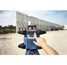 Logo Bosch. Laser rotatif sur un chantier avec une main touchant l''écran.