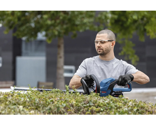 Mann schneidet Hecke mit einer Heckenschere von Bosch