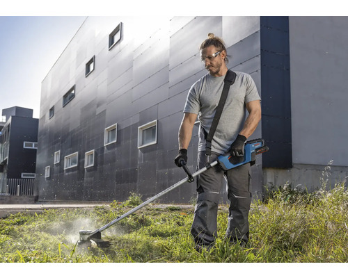 Mann schneidet Gras mit einem Akku-Rasentrimmer im Garten