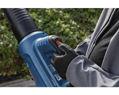 Eine Person bedient einen Laubbläser im Garten.