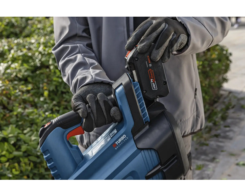 Eine Person setzt einen Akku in einen Heckenscherenkörper ein.