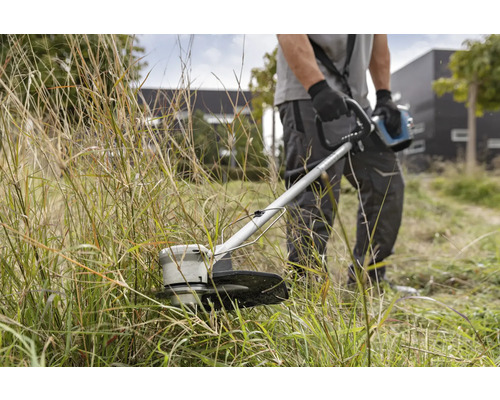 Mann schneidet Gras mit einem Rasentrimmer.