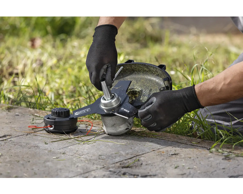 Ein Mann wechselt das Messer an einem Rasentrimmer.