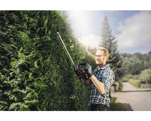 Mann schneidet Hecke mit Heckenschere