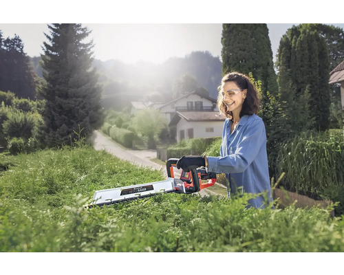 Frau schneidet Hecke mit einer Akku Heckenschere im Garten.