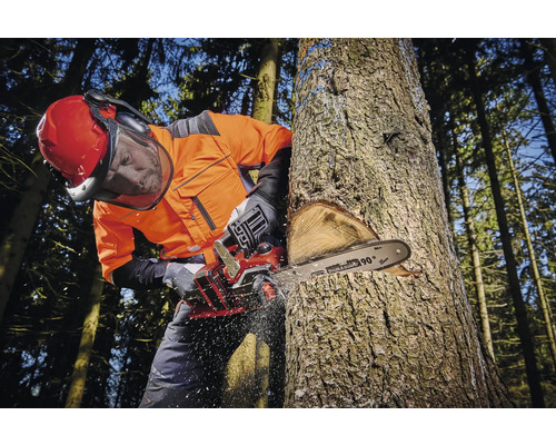 Homme portant des vêtements de protection coupant un arbre avec une tronçonneuse