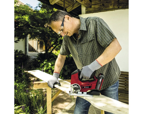 Mann sägt Holzbrett mit Stichsäge im Garten