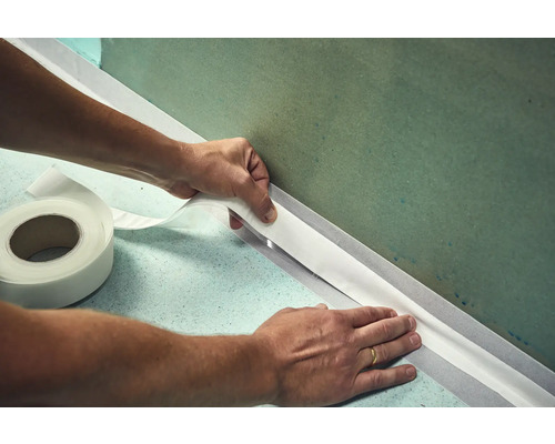 Mann bringt Dichtband an Wand an
