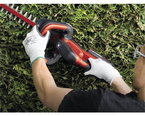 Eine Person schneidet mit einer Heckenschere eine Hecke.