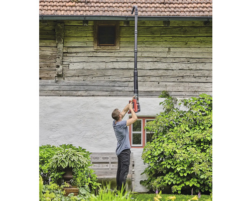 Eine Person reinigt eine Dachrinne mit einem Dachrinnenreiniger.