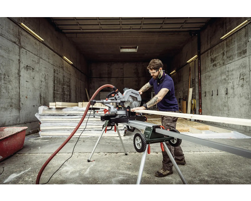Ein Mann schneidet ein Holzbrett mit einer Metabo Kappsäge auf einem Sägetisch.