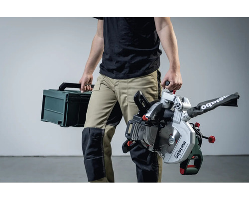 Eine Person trägt eine Metabo Kappsäge und einen Werkzeugkoffer.